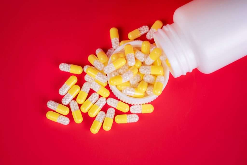 yellow gabapentin capsules poured from prescription drug bottle